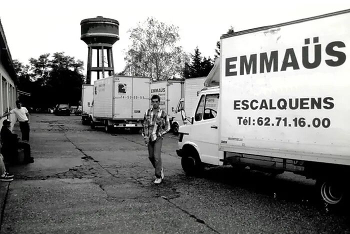 Photo historique du site Emmaüs à Escalquens. Compagnon devant un camion Emmaüs